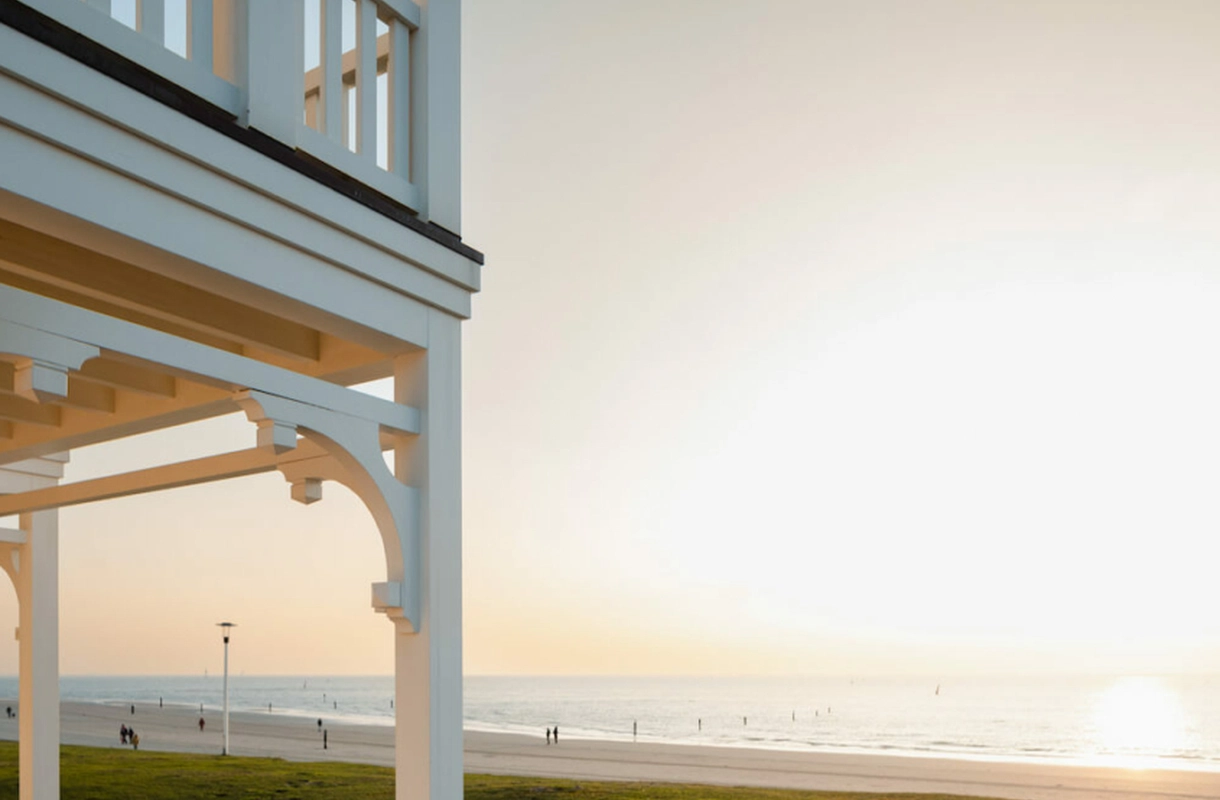 Blick entlang eines Balkons des Gebäudes auf die Nordsee beim Sonnenuntergang