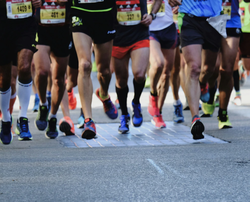 Läufer in sportlicher Kleidung nehmen an einem Straßenlauf teil, während sie die Straße entlang sprinten.